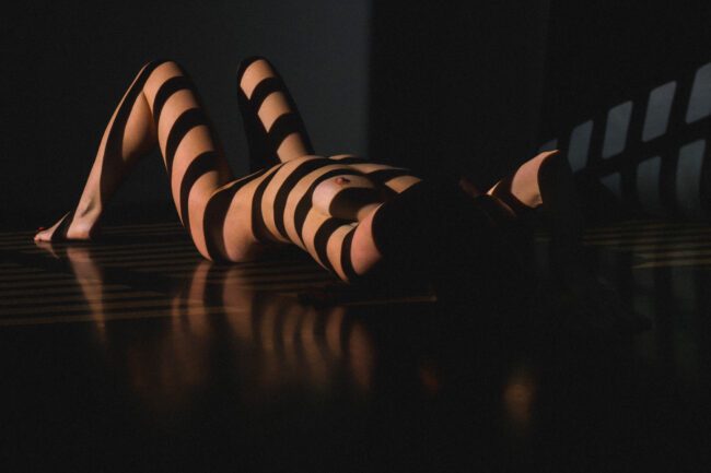 Unter Licht und Schatten liegende Frau in urbanem Fotostudio in Ehrenfeld