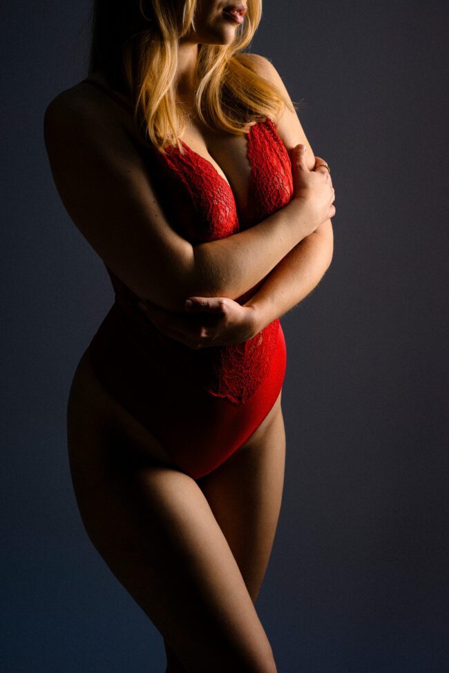 Frau in rotem Spitzen-Body vor dunklem Hintergrund, Aktfotografie im Kölner Studio