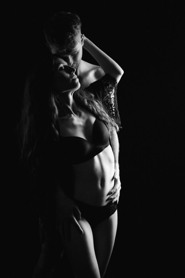 Schwarzweißaufnahme eines Paares in inniger Umarmung vor schwarzem Hintergrund