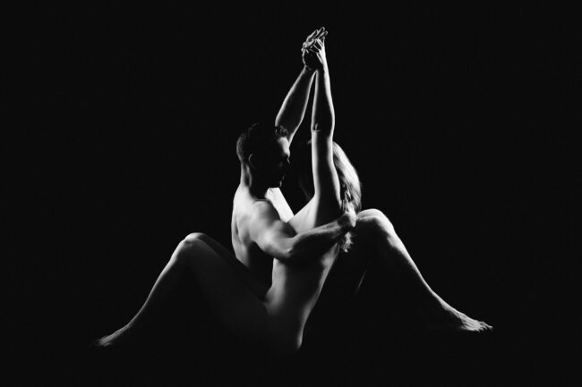 Ein Paar posiert nackt in einem kunstvollen Schwarz-Weiß-Fotoportrait im Fotostudio.